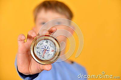 A child holds a compass in his hand and shows it to the camera, closeup. The concept of children`s travel and joining the ranks o Stock Photo