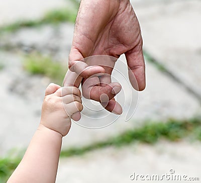 Child holds the finger of a hand of the father Stock Photo