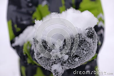 Child holds a lot of snow with gloved hands Stock Photo