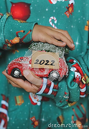 A child holds a New Year`s car in his hands with the year 2022 and dreams of a new toy Stock Photo