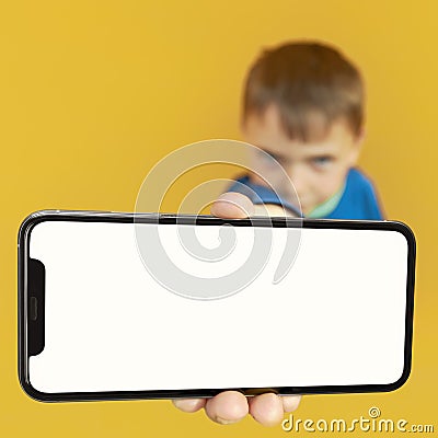 Child holds the phone in his hand for advertising on a yellow background. Color Stock Photo