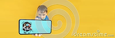 child holds the phone in his hand for advertising on a yellow background. Color Stock Photo