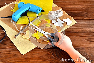 Child holds the scissors in his hands and does summer crafts with felt butterflies and flowers Stock Photo