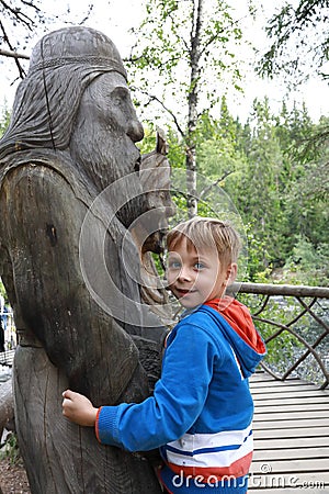 Child hugging wooden sculpture of viking god Stock Photo