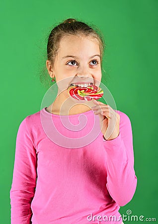 Child with hungry face poses with candy on green background. Stock Photo