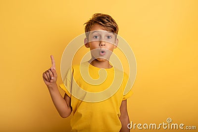 Child indicates above. Amazed and shocked expression. Yellow background Stock Photo