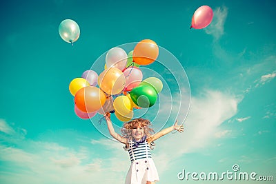 Child jumping with toy balloons in spring field Stock Photo