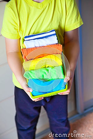 The child keeps his things. The boy puts the T-shirts in a drawer. Stock Photo