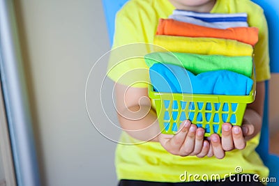 The child keeps his things. The boy puts the T-shirts in a drawer. Stock Photo
