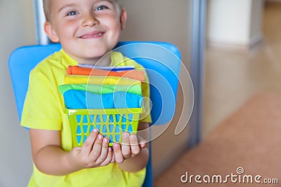 The child keeps his things. The boy puts the T-shirts in a drawer. Stock Photo