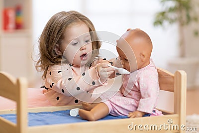 Child in kindergarten. Kid in nursery school. Little toddler playing with doll. Stock Photo