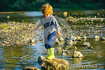 A child on the lake or river. The kid walks through the river. Walk in the park on a sunny spring day. The boy looks at Stock Photo