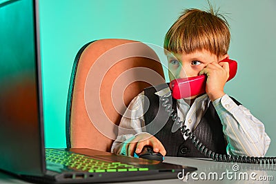 A child at a laptop in the office agrees on matters by wire, the concept of modern children`s business Stock Photo