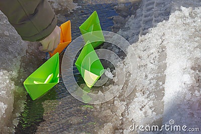 The child launched paper boats made of green paper into the stream in the spring Stock Photo