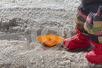 The child launched paper boats into the stream in the spring and walks along the streams from the melting snow on the Stock Photo