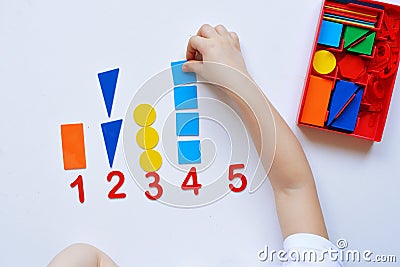 The child learns Number line and geometric shapes. The preschooler works with Montessori material. Educational logic toys for kid Stock Photo