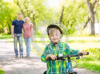 The child learns to ride a bike with his parents in the park Stock Photo