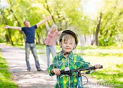 The child learns to ride a bike with his parents in the park Stock Photo