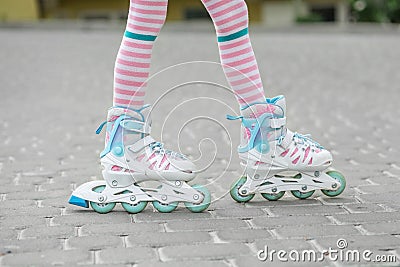 The child learns to roller skate. Girl in pink tights. Childhood and hobby concept Stock Photo