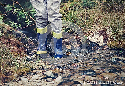 Child legs in gum boots into the forest creek Stock Photo