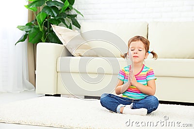 Child little girl meditates in lotus position and practices yoga Stock Photo