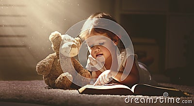 Child little girl reading a magic book in dark home Stock Photo