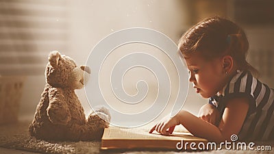 Child little girl reading a magic book in dark home Stock Photo