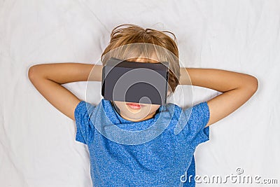 Child liying on bed with 3D Virtual Reality, VR cardboard glasses Stock Photo