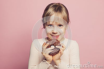 Child llittle girl holding donut on pastel pink background Stock Photo