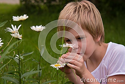 The child looked carefully at the flowers on a green meadow. Curiosity and the study of the environment. nature. Stock Photo