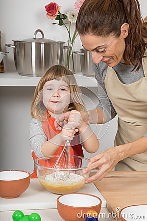 Child looking and whipping to make a cake with mother Stock Photo