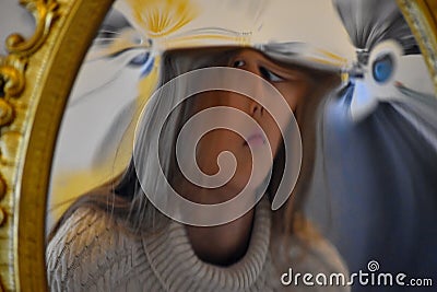 The child looks into a distorting mirror. The reflection in the silver glass Stock Photo