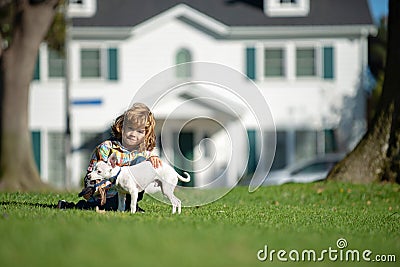 Child lovingly embraces his pet dog. Happy little kid boy playing with puppy in garden. Stock Photo