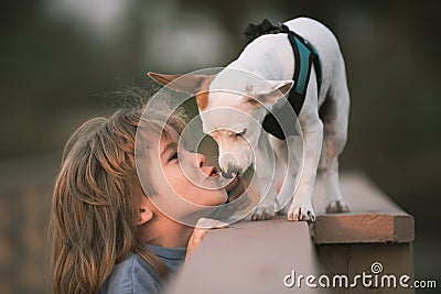Child lovingly embraces and kisses his pet dog. Stock Photo