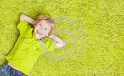 Child Lying Over Green Carpet. Happy Smiling Kid Boy Stock Photo
