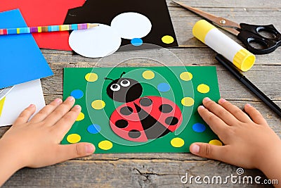 Child made a ladybird from colored paper. Summer card with paper ladybug, stationery on a wooden table. Simple paper circle crafts Stock Photo