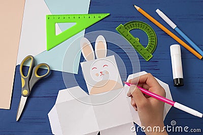 Child makes box for sweets in form of Easter Bunny. Step 7 Stock Photo
