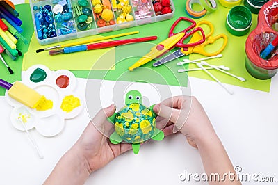 The child makes a craft toy from foam plastic tortoise. Material for creativity and education Stock Photo