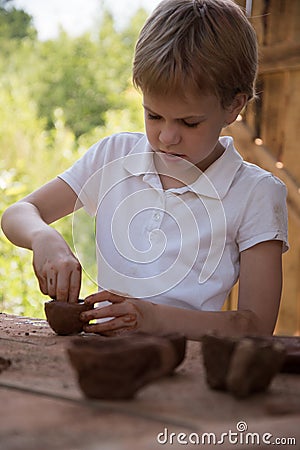 The child makes dishes and various figures from clay. Pottery skills. Hobbies and interests. Children`s education Stock Photo