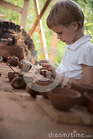 The child makes dishes and various figures from clay. Pottery skills. Hobbies and interests. Children`s education Stock Photo