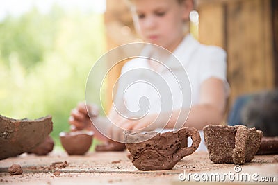 The child makes dishes and various figures from clay. Pottery skills. Hobbies and interests. Children`s education, expanding Stock Photo