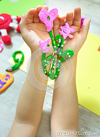 Child making bouquet, flowers from plasticine, clay, beads. little girl creating gift for mom gift for Mothers day, Birthday or Stock Photo