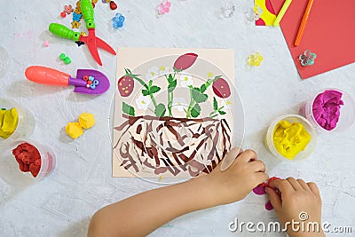 Child making harvesting of fresh red strawberry fruit from paper and plasticine, applique. Crafts for children. Children Stock Photo
