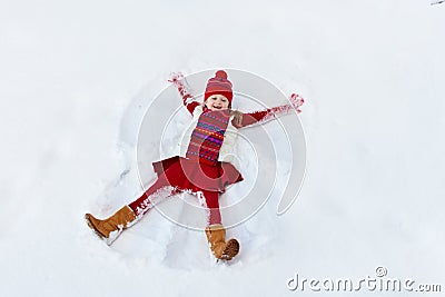 Child making snow angel on sunny winter morning. Kids winter outdoor fun. Family Christmas vacation. Little girl playing in snow Stock Photo