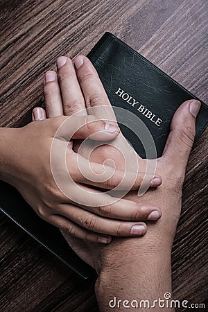 Child and Man Hands On The Bible Stock Photo