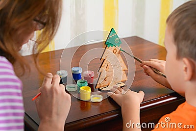 The child and Mother paints a wooden New Year`s Christmas tree. Little boy and mother draws a new-year tree Stock Photo