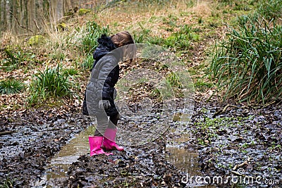 Child in mud on track through woodland Stock Photo