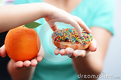 Child obesity concept with little girl hand choosing a sweet and unhealthy doughnut instead of a fruit Stock Photo
