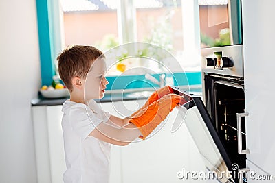 Child opening oven in kitchen. Stock Photo