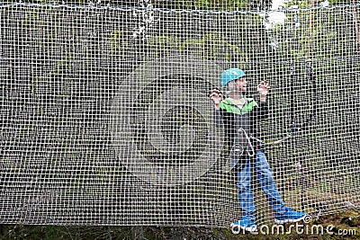 Child overcoming mesh obstacle in rope adventure park Stock Photo